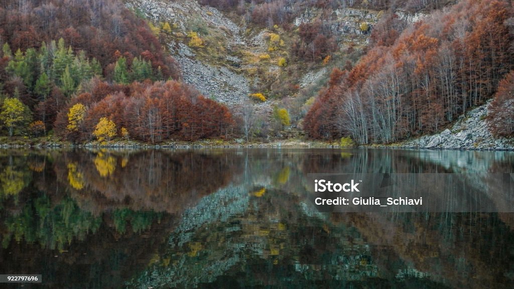 Mountain, trees and fall foliage in perfect lake reflections (Lago Santo, Modena, Italy) Peaceful evening at the Lago Santo in the Italian northern Apennine mountains. The various shades and colors of the autumn leaves are immortalized and reflected in the calm water of the lake. Letter X Stock Photo