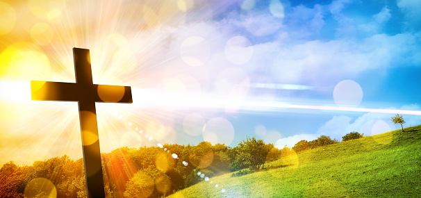 Religious illustration with backlit cross with golden glitter and bokeh and nature landscape background. Horizontal composition