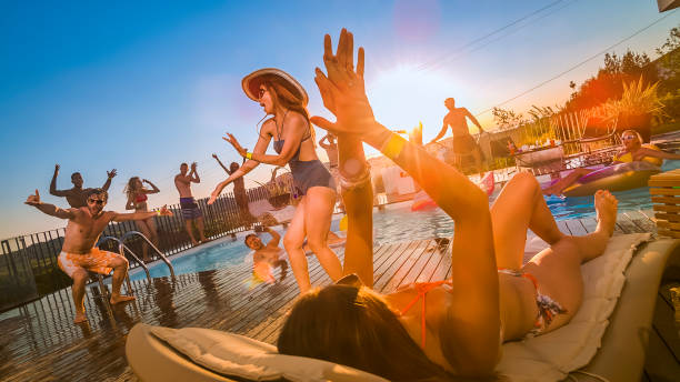 personnes à la piscine partie danser et sauter dans la piscine au coucher du soleil - floatation device flash photos et images de collection