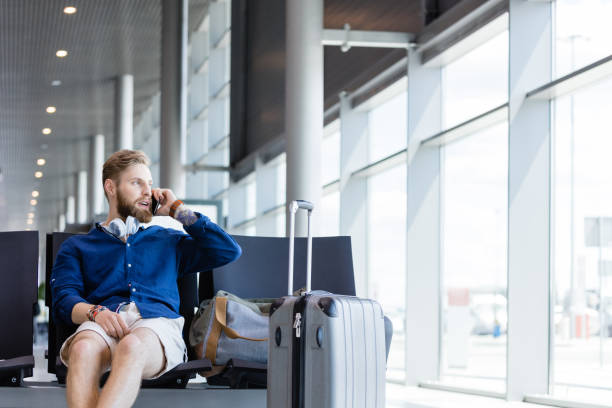 istock Young bearded man talking on phone in airport lounge 922799106