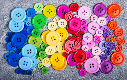 Colorful plastic clothing buttons on a gray stone background