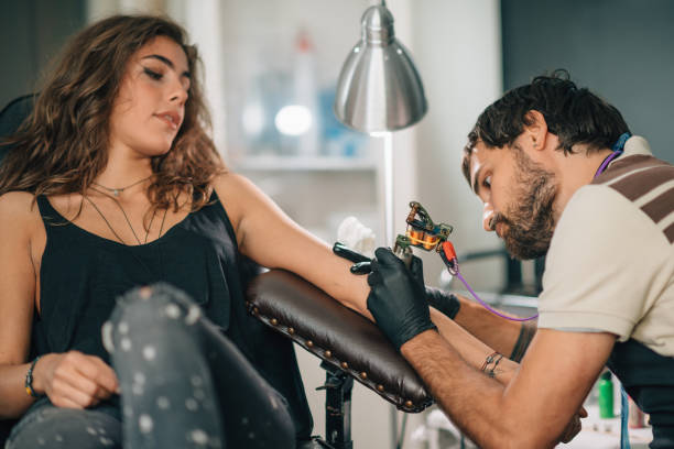 artista che fa tatuaggio sulla mano della donna in studio - tatuare foto e immagini stock
