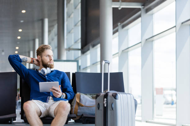 istock Young bearded man using digital tablet in airport lounge 922803018
