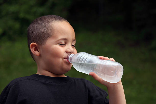 istock Smiling young boy drinking water from bottle in park 92280829