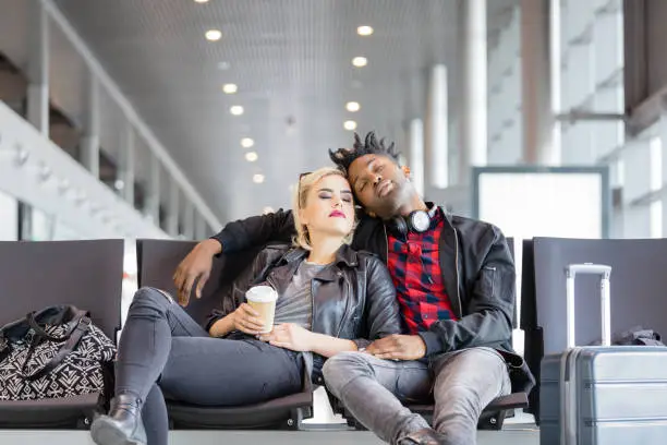Photo of Multi ethnic funky couple waiting for flight in airport lounge