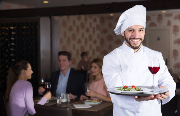 istock Chef with serving tray meeting restaurant guests 922814636
