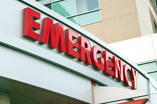 Close up photo of red large letters spelling emergency Large red EMERGENCY sign on hospital entrance. Raw original. emergency room stock pictures, royalty-free photos & images