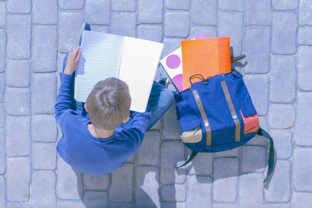 istock Child sitting on the ground and flipping through notebook pages 922825840