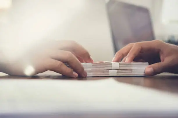 Photo of Close up of businessman hand giving money, Russian banknotes, to his partner on the table