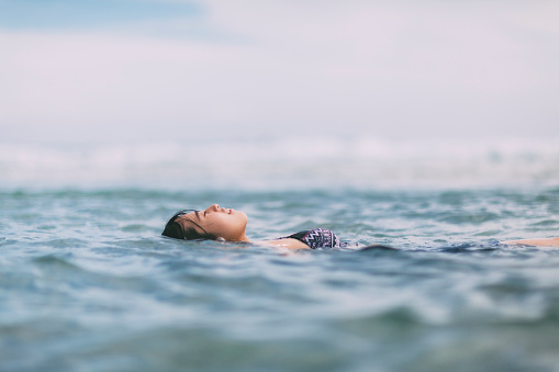A young Japanese woman is floating in the sea.