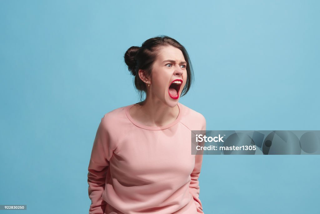 Die junge emotionale böse Frau schreiend auf blauen Studio-Hintergrund - Lizenzfrei Wut Stock-Foto