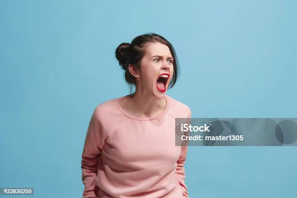 Die Junge Emotionale Böse Frau Schreiend Auf Blauen Studiohintergrund Stockfoto und mehr Bilder von Wut