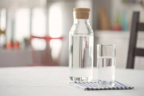istock Water bottle and glass of water on kitchen table 922835704