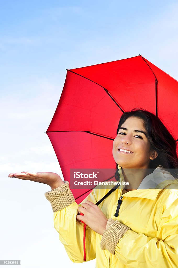 Bellissima giovane donna in impermeabile con ombrello controllando per la pioggia - Foto stock royalty-free di Adulto