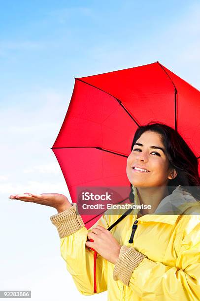 Bellissima Giovane Donna In Impermeabile Con Ombrello Controllando Per La Pioggia - Fotografie stock e altre immagini di Adulto