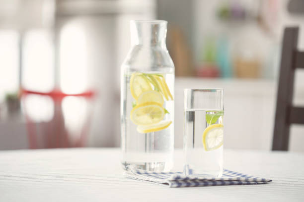 bouteille d’eau et le verre d’eau avec du citron dans la cuisine - waterlemon photos et images de collection