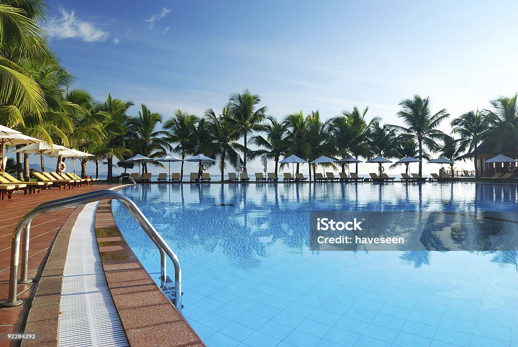 Poolside view of tropical pool surrounded by palm trees Tropical pool in luxury hotel Resort Swimming Pool Stock Photo