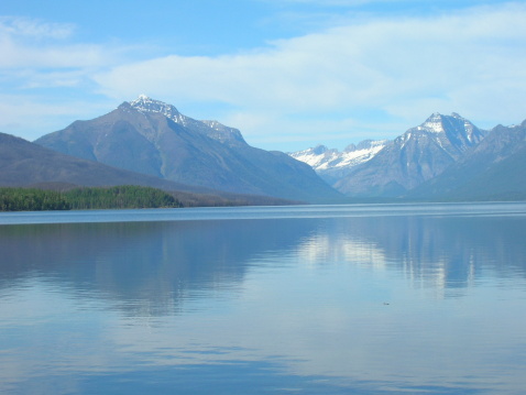 Mountain peaks are reflected in the waters of Lake Sherburne, which is located in the Many Glacier region of Glacier National Park, Montana.