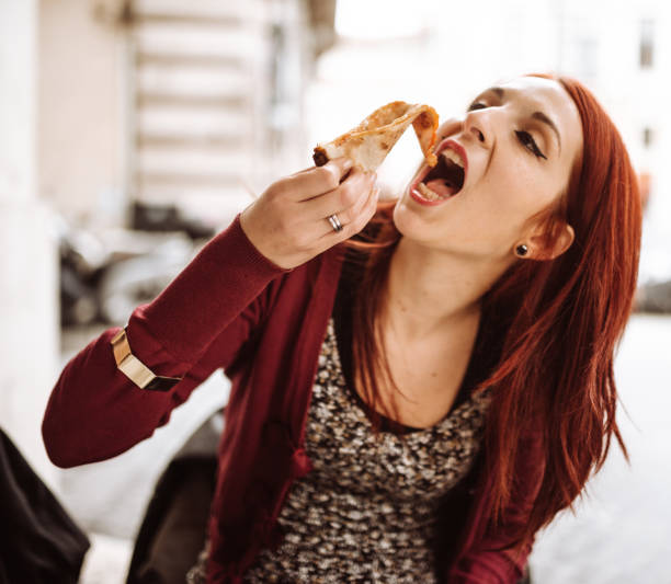 istock woman eating pizza in italy 922854670