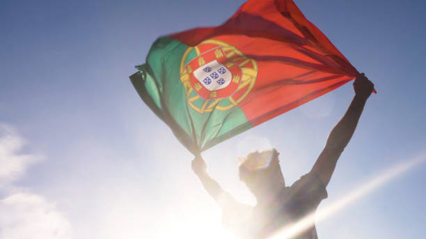 青年男子手持葡萄牙國旗, 兩只手在海灘日落葡 萄牙的天空 - 葡萄牙 個照片及圖片檔