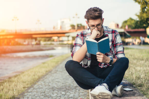 istock Young man reading book outdoor. 922858256