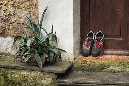 Two trekking shoes are left outside a rustic house for drying