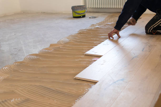 Renovation of an apartment, skilled worker uses a plastic hammer when installing pre-finished interlocking parquet. stock photo