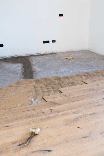 istock Oak colored parquet during installation on an old stoneware floor near an open window. 922864726