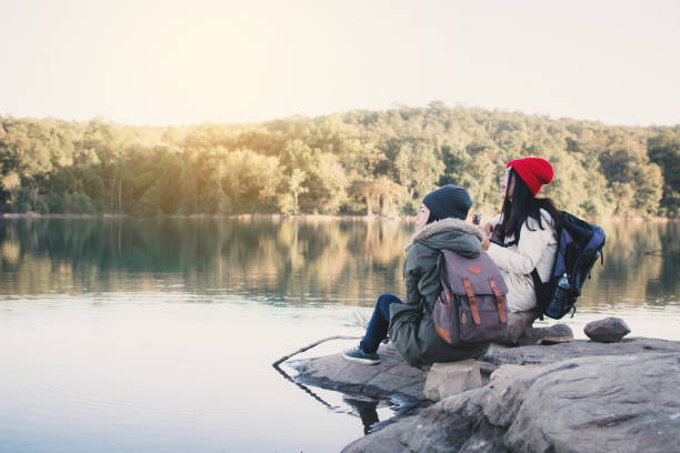 istock Friends Sitting By Lake On Rock 922865142