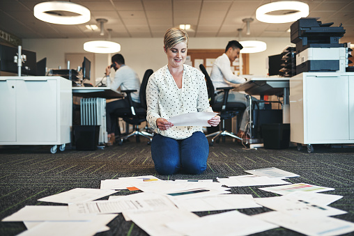 Shot of a businesswoman working with paperwork on the floor in the office