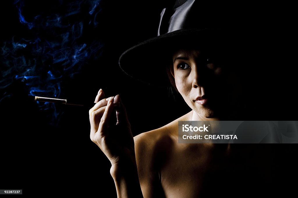 Woman in shadow wearing a black hat with cigarette  Addiction Stock Photo