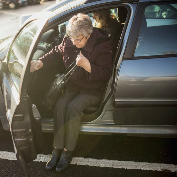 senior mujer saliendo de un coche - car for sale fotografías e imágenes de stock