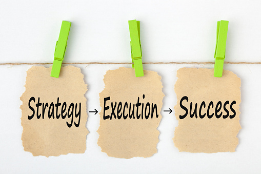 Strategy Execution Success writen on old torn paper with clip hanging on white background.Business concept words.