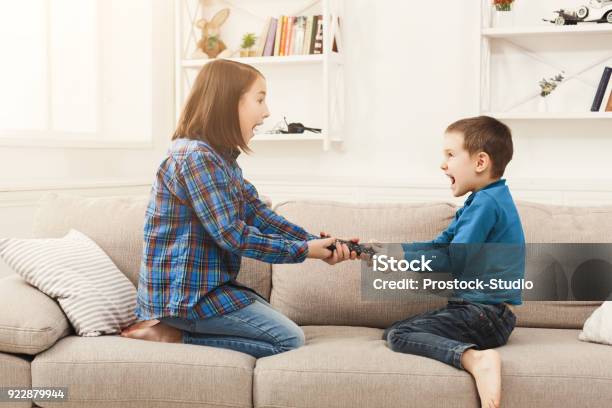 Siblings Fighting Over Remote Control At Home Stock Photo - Download Image Now - Arguing, Fighting, Child