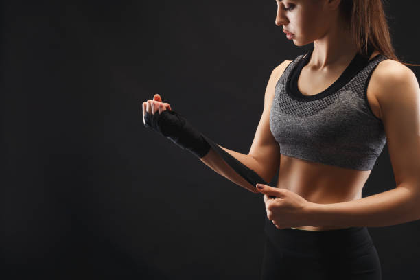 Athletic boxer wrapping hands with boxing bandage