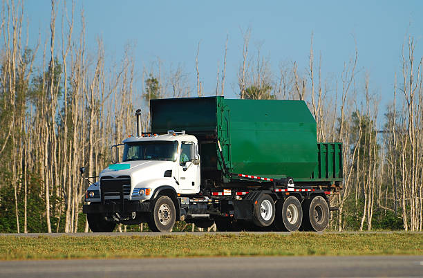 Green garbage truck driving down the road stock photo