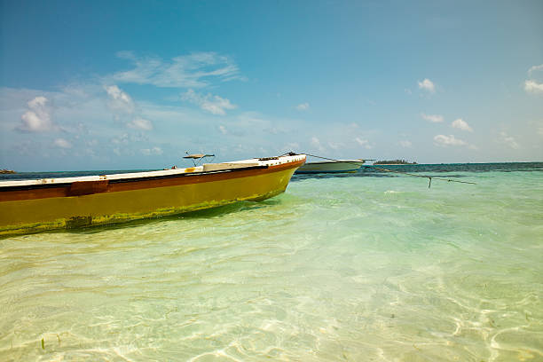 Beautiful caribbean sea and boat on the shore of exotic tropical island, panoramic view from the beach