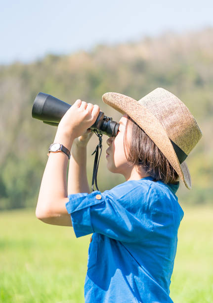istock Woman wear hat and hold binocular in grass field 922897798
