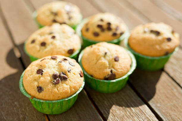Close-up on baked chocolate muffin in wax paper cup, served on grid