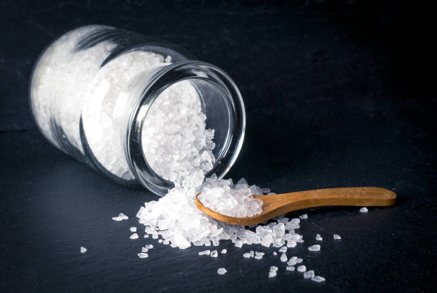 istock Sea salt with spoon and jar on dark background 922904874