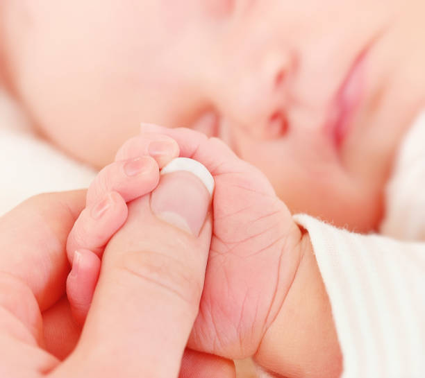 istock Newborn Baby Holding Mother's Finger 922907704
