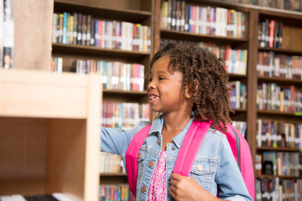 istock African descent little girl in school library choosing book. 922908008