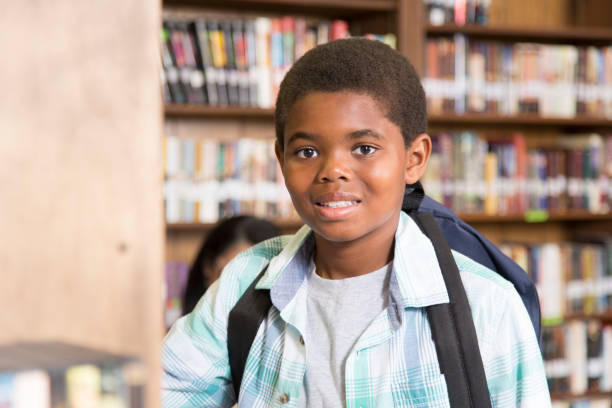 istock African descent boy choosing book in school library. 922912414