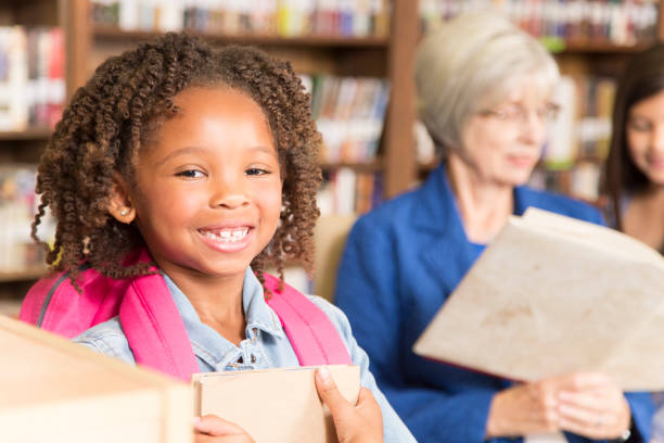 istock African descent little girl in school library with book. 922913012