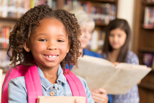 istock African descent little girl in school library with book. 922913216