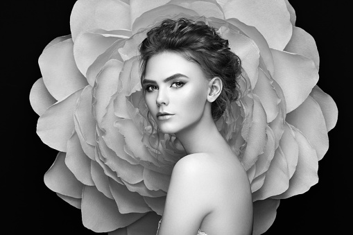 Beautiful woman on the background of a large flower. Beauty summer model girl with peony. Young woman with elegant hairstyle and makeup. Fashion photo