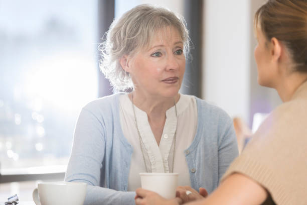 senior woman has serious conversation with daughter - consumer exposure imagens e fotografias de stock