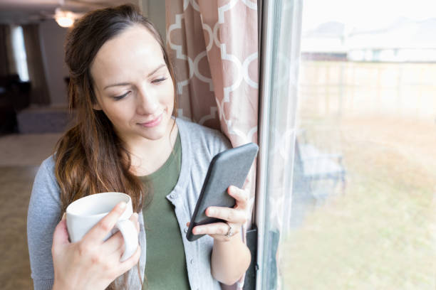 istock Beautiful woman uses mobile app as she drinks her morning coffee 922942512