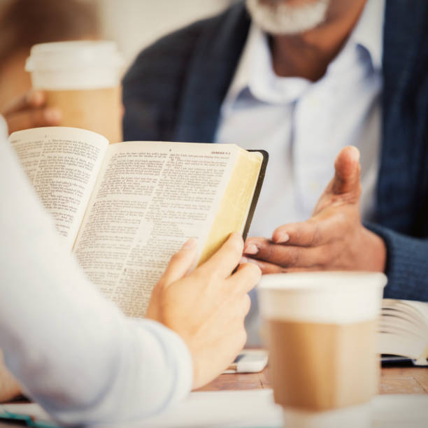 Unrecognizable man and woman participate in Bible study. The man gestures as the woman holds the Bible.