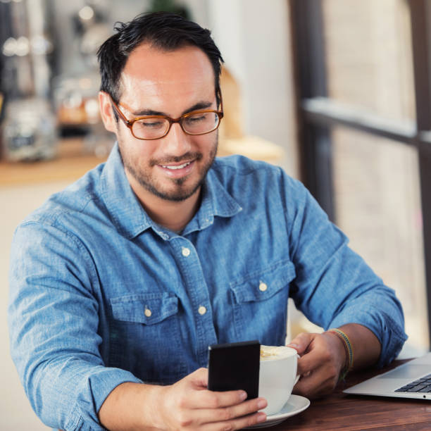 istock Handsome man uses smart phone while in coffee shop 922943800